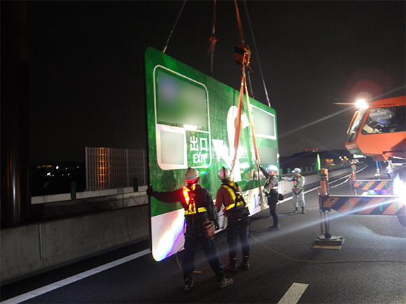 交通安全施設工事　 新名神高速道路　城陽ジャンクション標識工事　 高速道路の門型柱への案内標識板吊上げ状況写真（その１）
