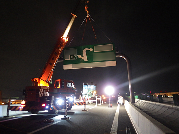 交通安全施設工事　 新名神高速道路　城陽ジャンクション標識工事　高速道路の門型柱への案内標識板吊上げ状況写真（その2）